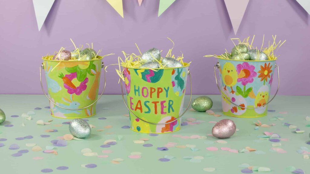 Easter gift buckets with spring-themed designs filled with chocolate eggs.
