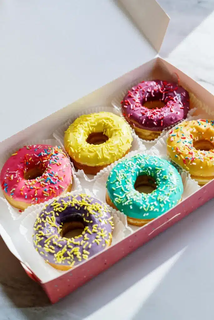 Glazed doughnuts in cardboard box with white paper liners.