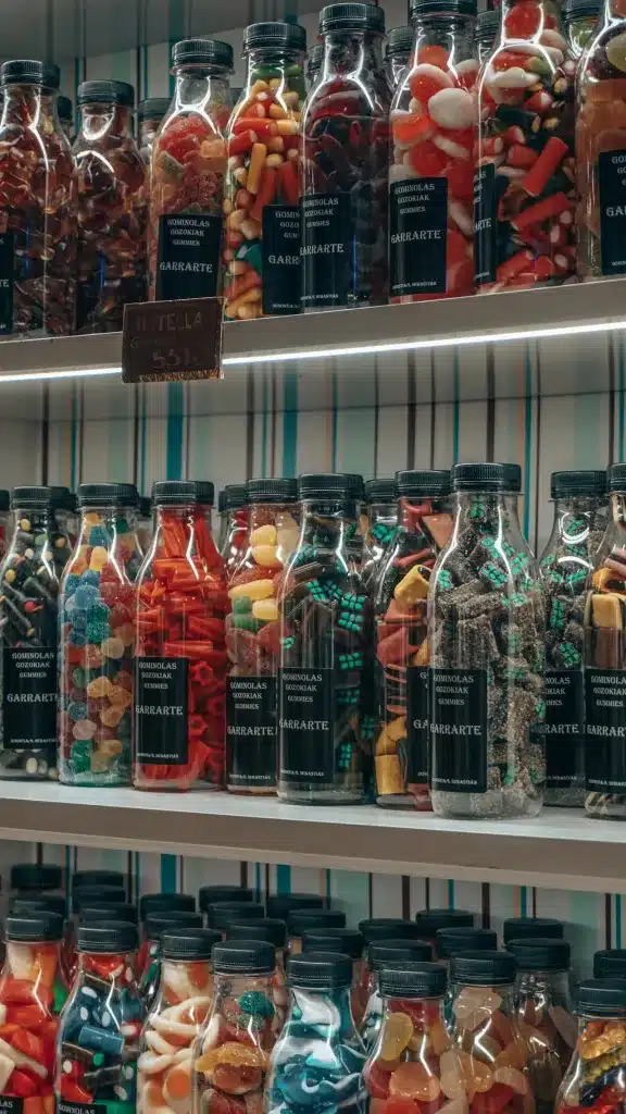 Colourful sweets and gummies in glass bottles with metal lids demonstrating glass food packaging types for confectionery.